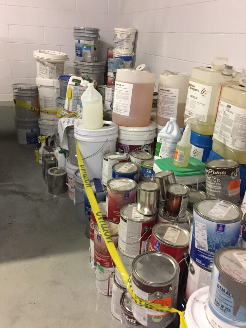 Many buckets of paint are lined up in a room.