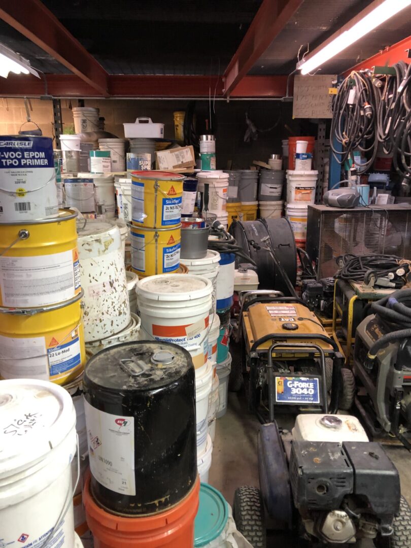 Many buckets of paint in a garage.