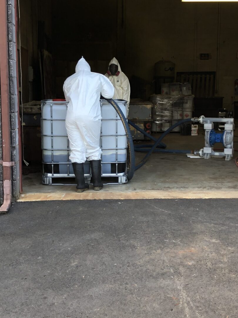 Two people in protective suits working in a warehouse.