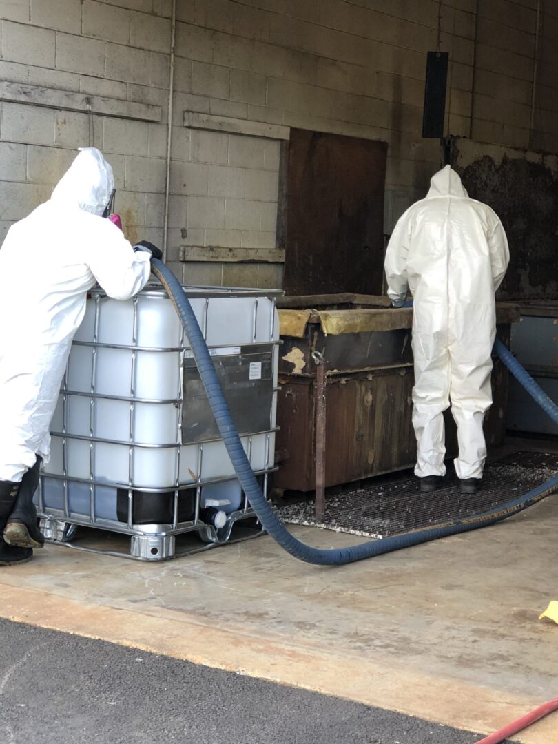 Two men in protective suits working in a warehouse.