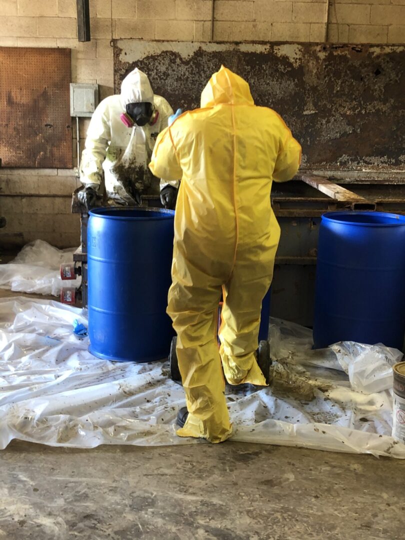 Two people in protective suits working in a warehouse.