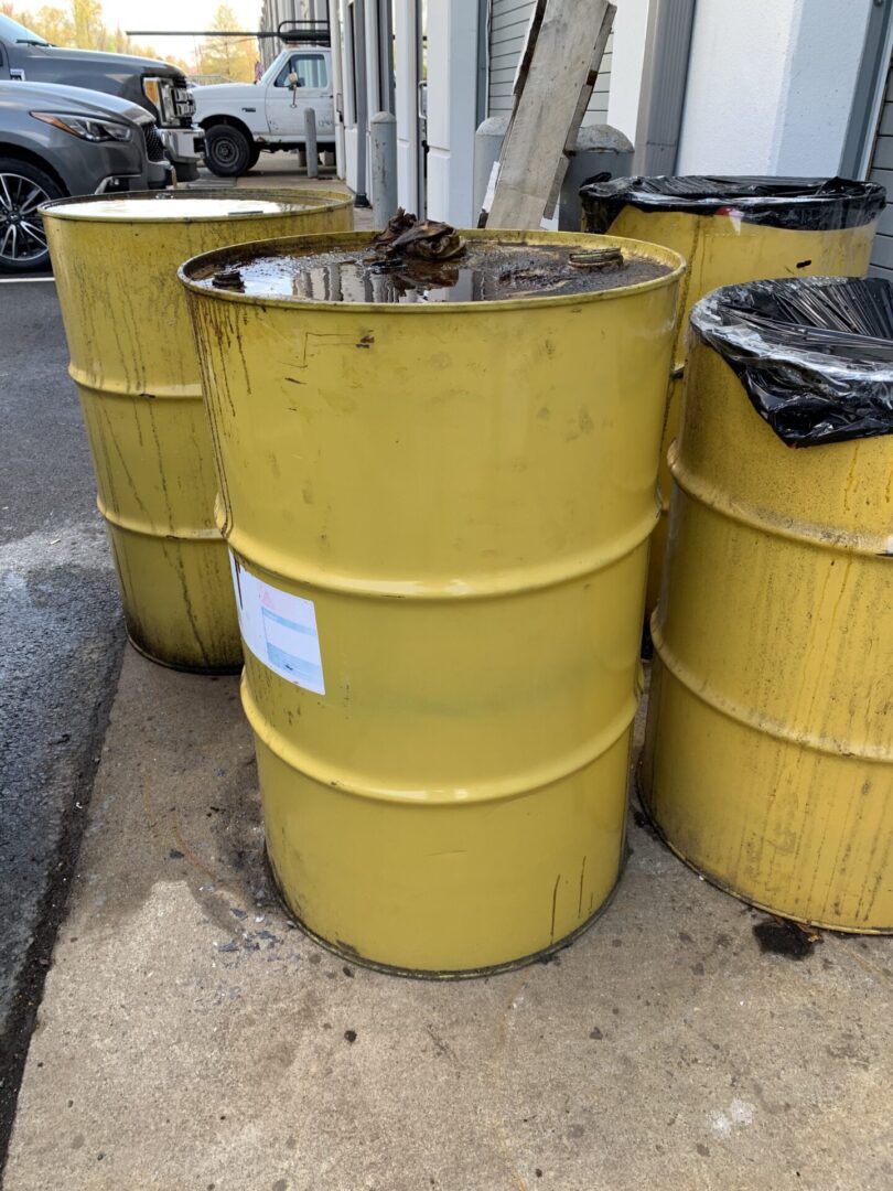 Three yellow barrels sitting outside of a building.