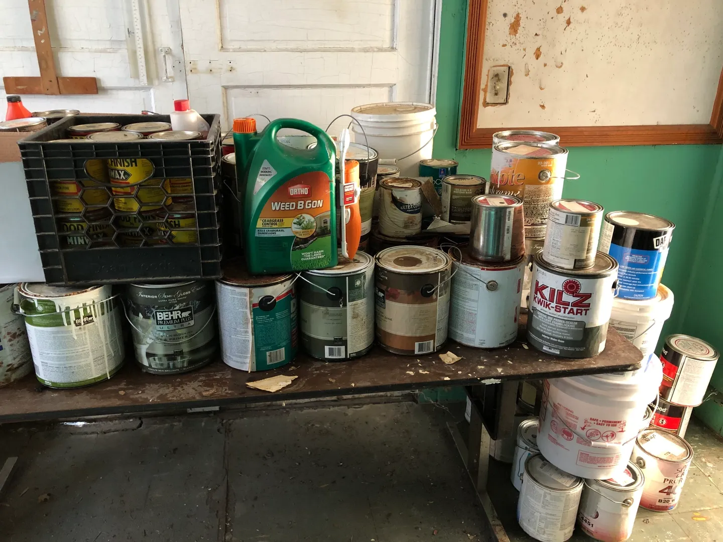 A wooden table full of paint cans and other containers.