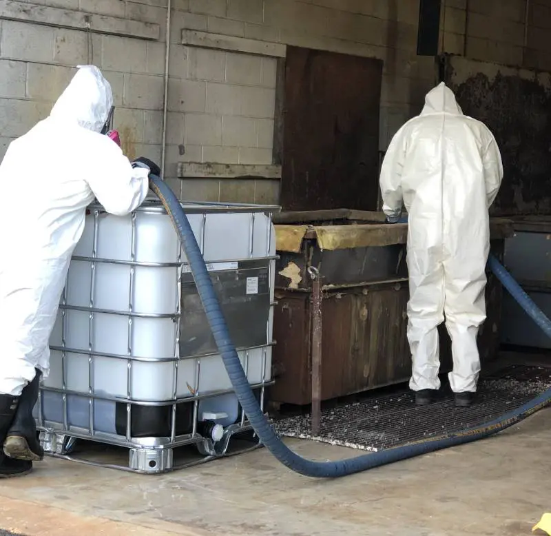Two hazmat workers cleaning up a chemical spill.